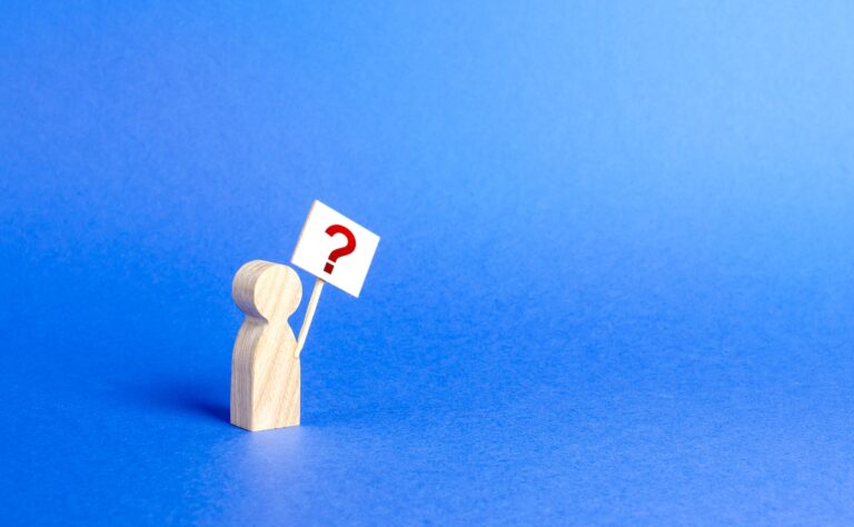 Wooden figure holding sign with question mark