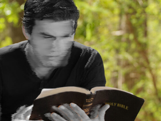 A blurred image of a young man reading a Bible.