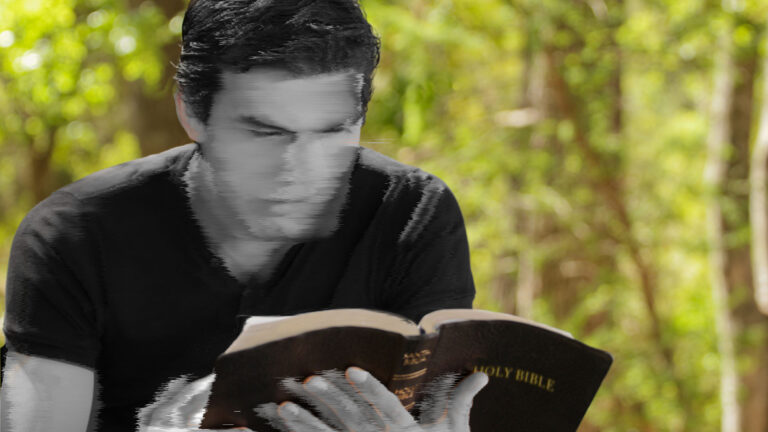 A blurred image of a young man reading a Bible.