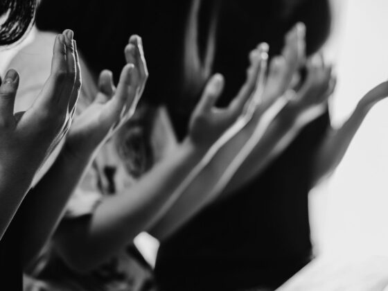 Several people's raised hands, just showing their torsos and hands.