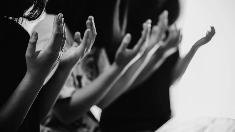 Several people's raised hands, just showing their torsos and hands.