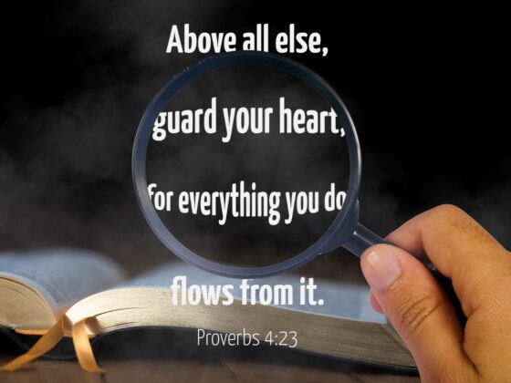 A magnifying glass looking at the verse Proverbs 4:23 over an image of an open bible, exaggerating the center part of the verse, which reads "Above all else, guards your heart, for everything you do flows from it."