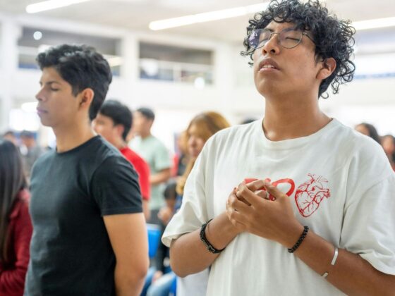 A brightly lit room full of young people in worship.