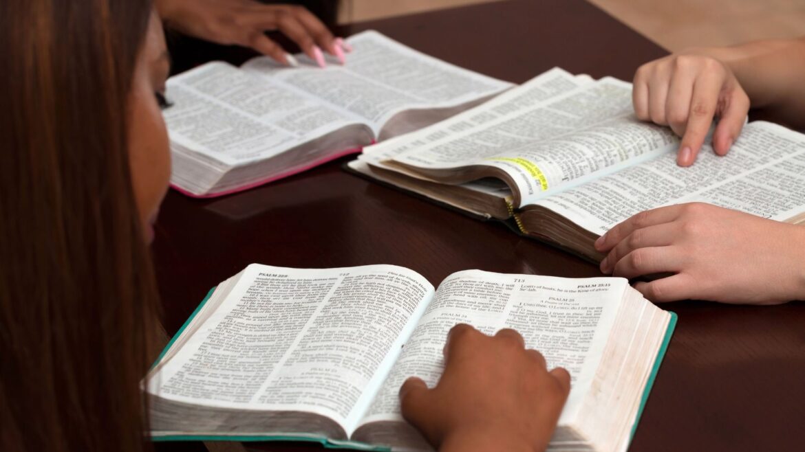 Tabletop with 3 people's hands on 3 open bibles.