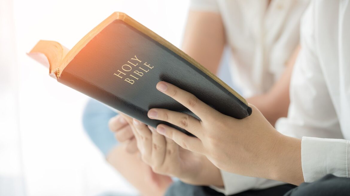 Person holding a Holy Bible, symbolizing cultivating deep affection for Christ in Christian school culture