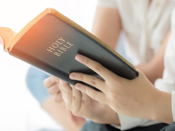 Person holding a Holy Bible, symbolizing cultivating deep affection for Christ in Christian school culture