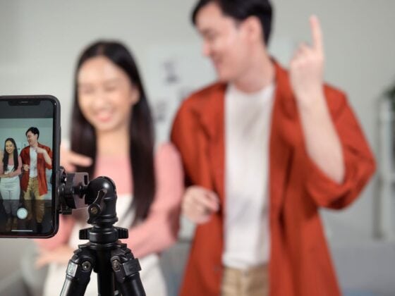 Teenagers recording a short-form video on a smartphone tripod, illustrating how social media content like TikTok and YouTube shapes student behavior and worldview
