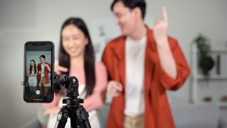 Teenagers recording a short-form video on a smartphone tripod, illustrating how social media content like TikTok and YouTube shapes student behavior and worldview