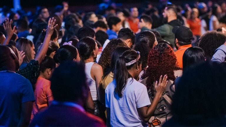 Students gathered in a worship service, with raised hands and bowed heads, illustrating the question of whether chapel participation becomes lasting worship after graduation.