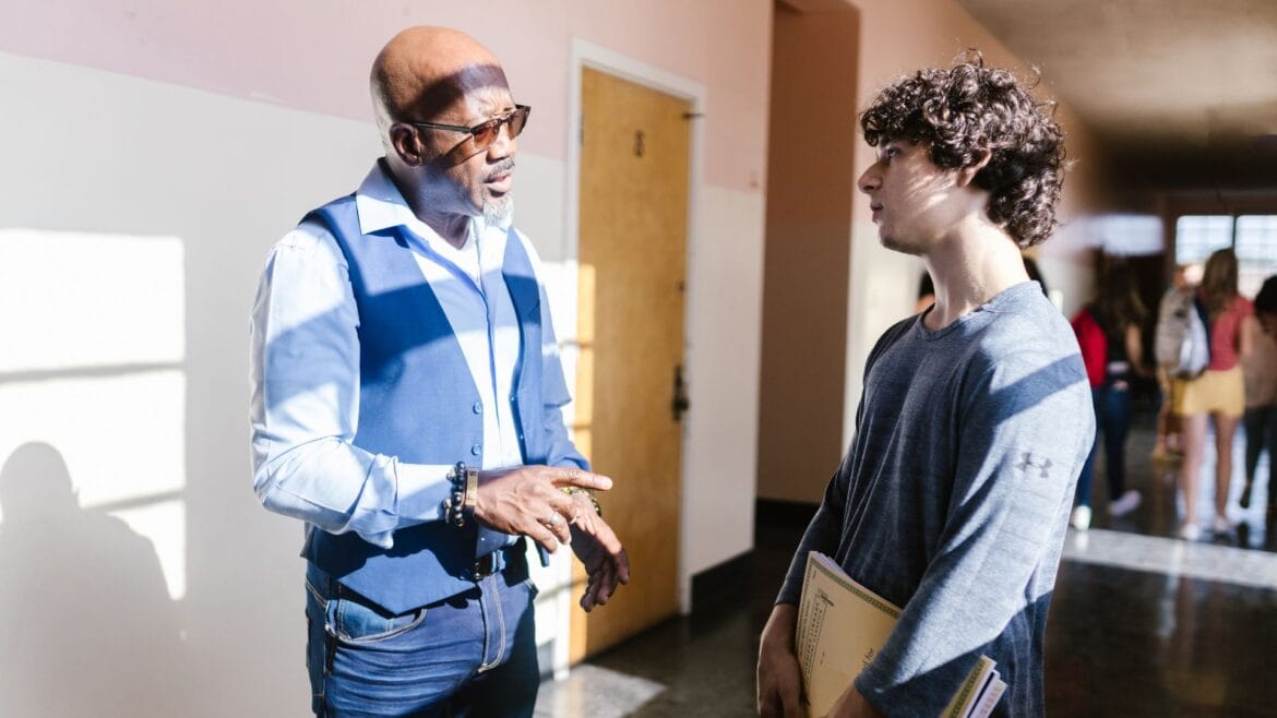 Adult mentor speaks with a student in a school hallway during a conversation about biblical worldview.