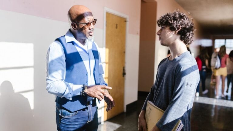 Adult mentor speaks with a student in a school hallway during a conversation about biblical worldview.